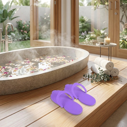 Purple flip-flops and rolled towels with foot spa bowl and flower petals