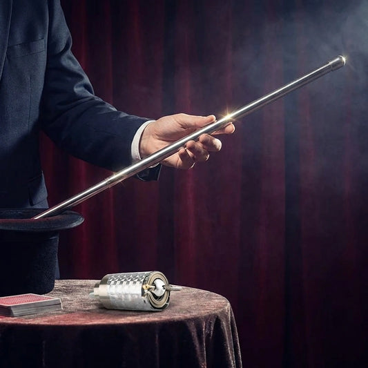 Silver magic cane toy wand held in hand with base on table