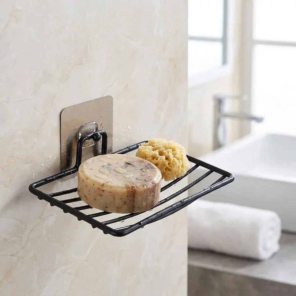 Wall-mounted soap rack with black wire frame holding round soap and sponge