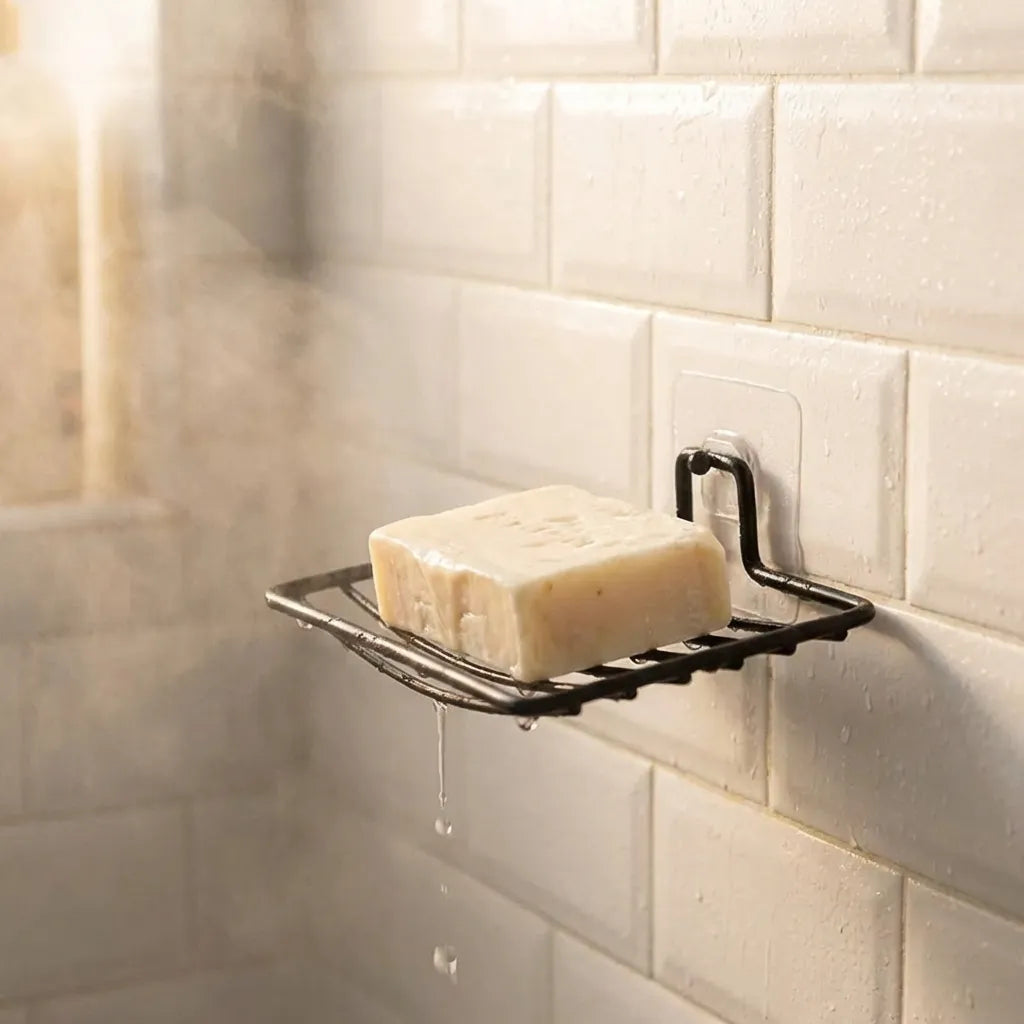 Wall-mounted metal soap rack holding a pale bar of soap on a tiled wall