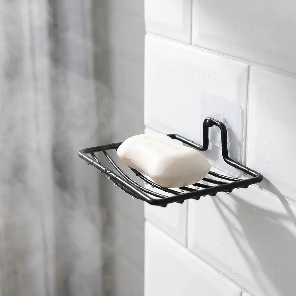 Wall-mounted black soap rack holding a white soap bar and wire base