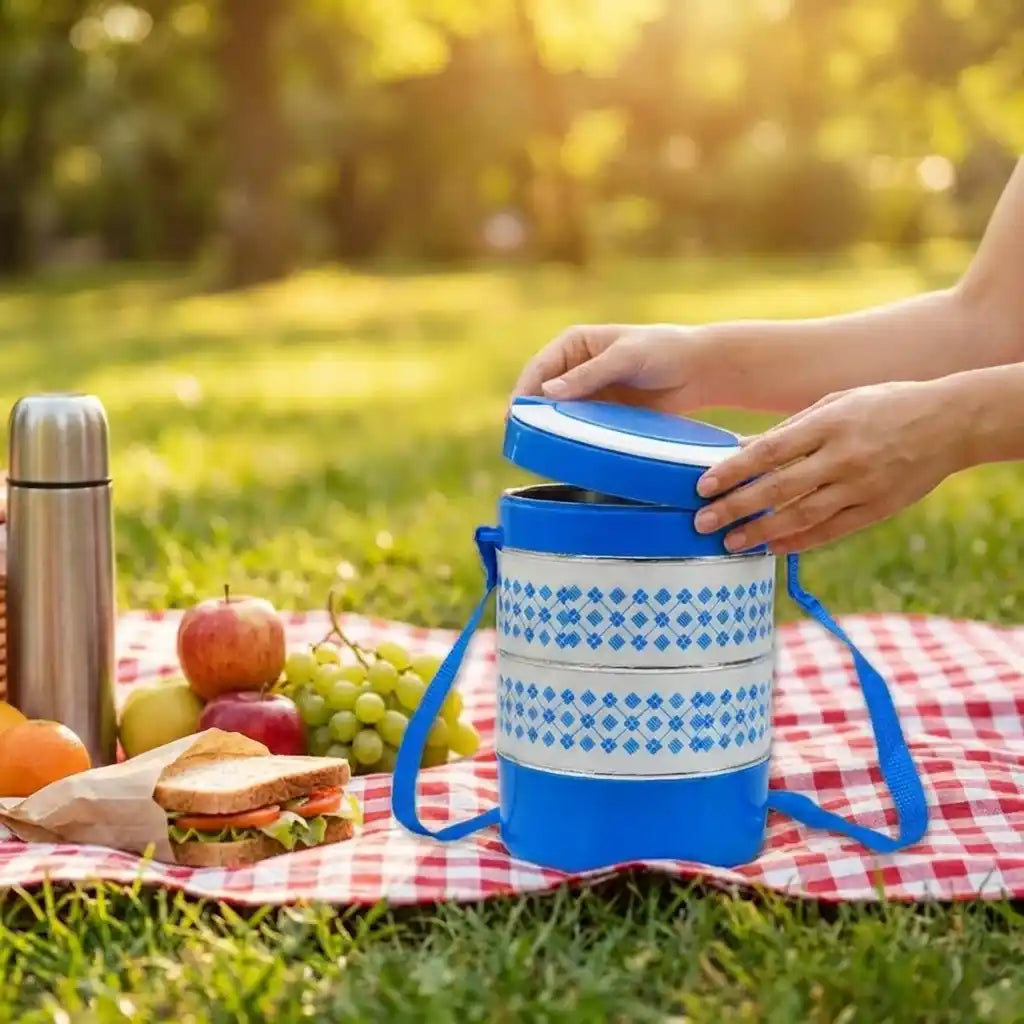 Blue patterned tiffin set with white lid lifted by blue carry strap
