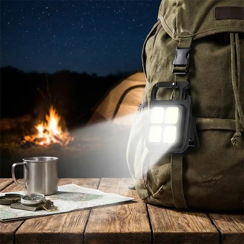 Mini keychain light with 4 LEDs, clipped to a bag