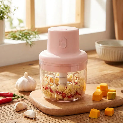 Pink mini garlic chopper with transparent bowl and chopping lid, visible garlic pieces