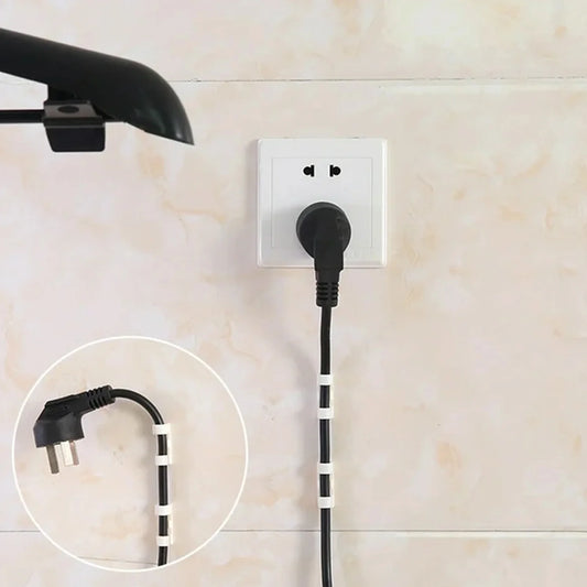 Adhesive cable clips holding a black power cord near a wall outlet