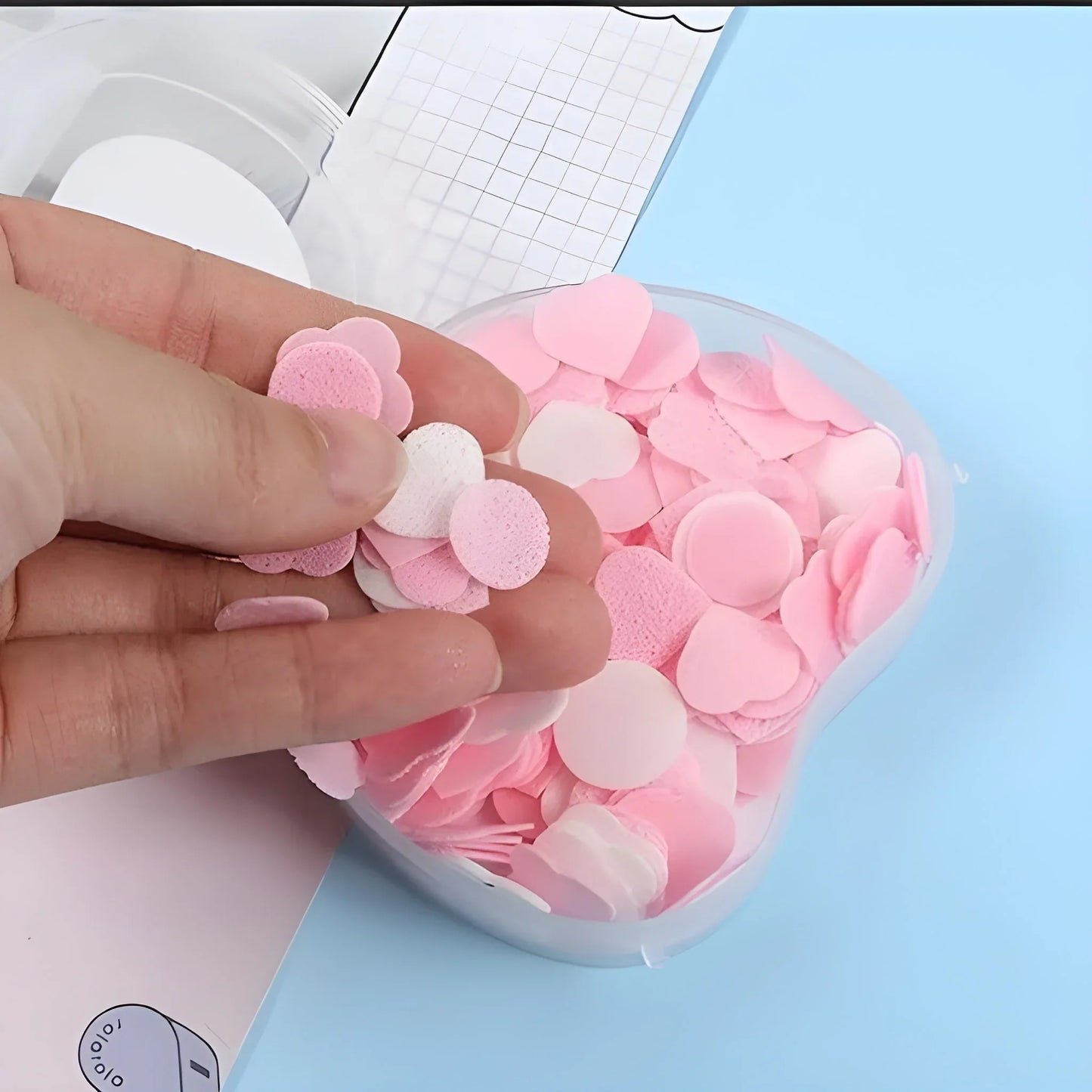 Soft paper soap sheets in pink, round and layered, held in a hand