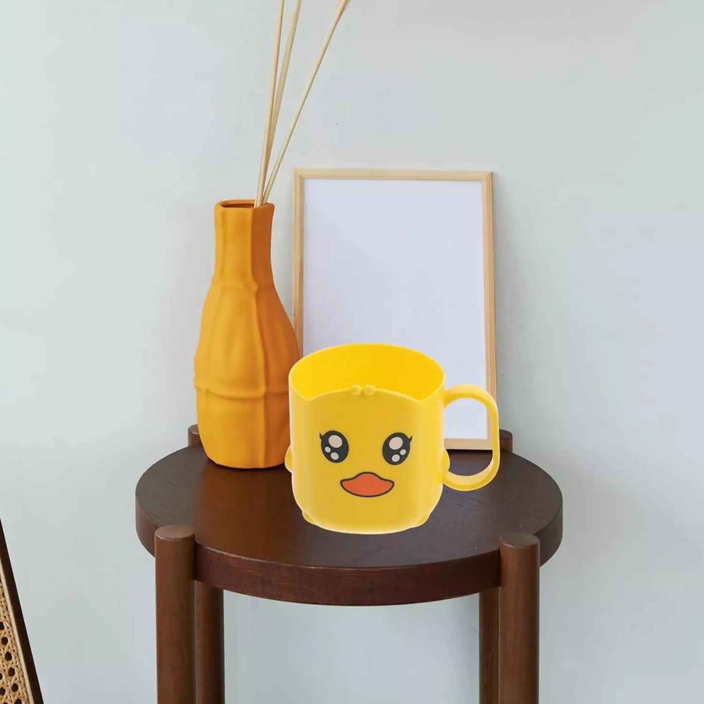 Yellow cartoon toothbrush cup with handle and smiling face design