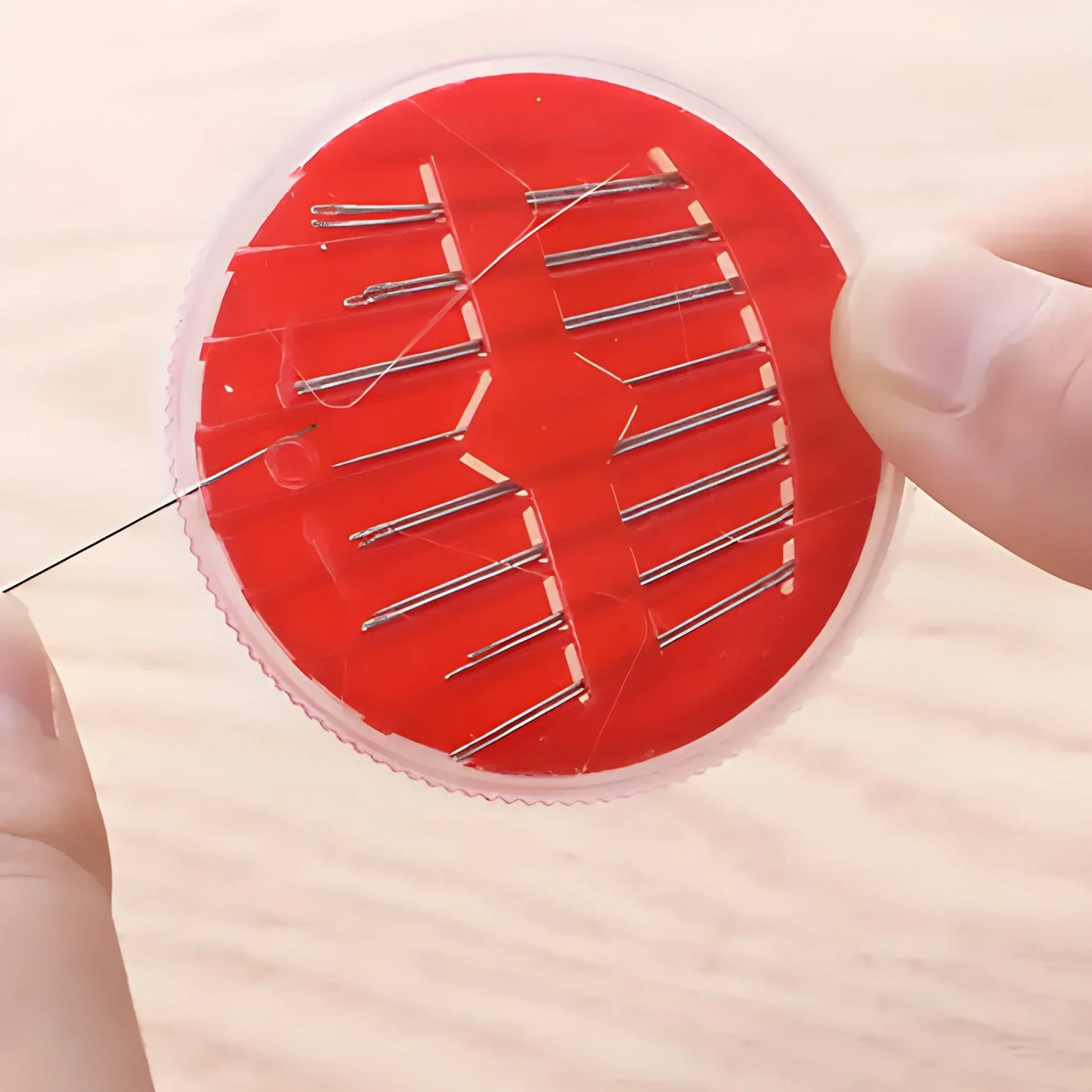 Round red pin cushion with assorted sewing needles