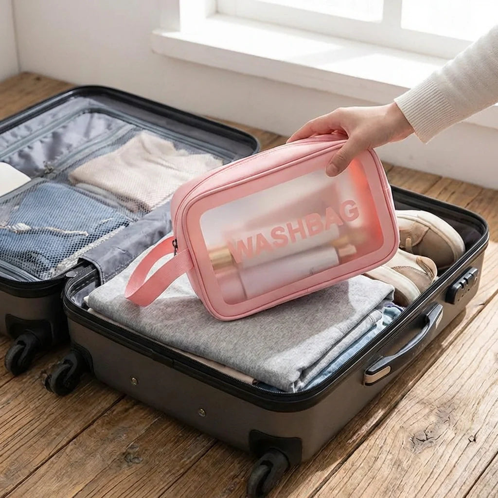 Pink cosmetic wash bag open with clear front panel and zipper, wrist strap