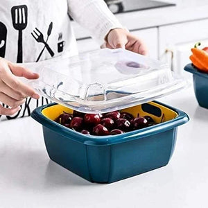 Blue double-layer food colander with clear top, held over mixed fruit