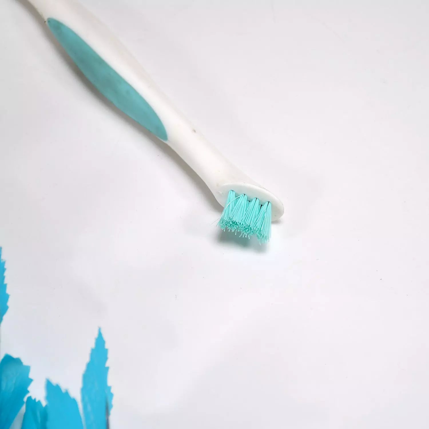 Dual-sided cleaning brush with teal bristles and white handle
