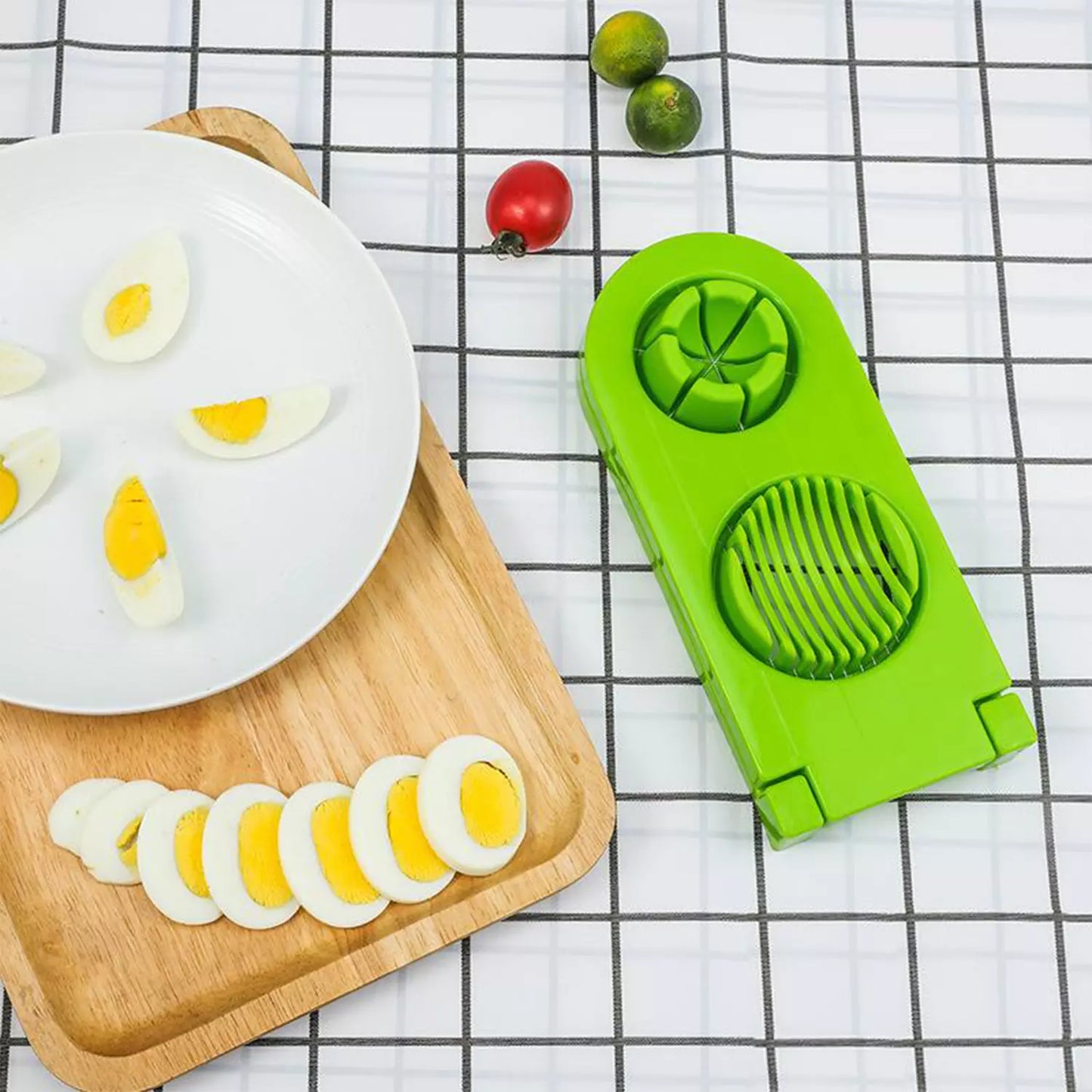 Green egg slicer and cutter with sliced boiled eggs on wooden board.