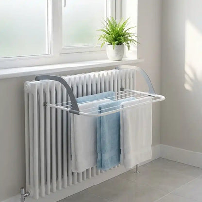 Folding clothes drying rack with white frame, drying towels and shirts by a window