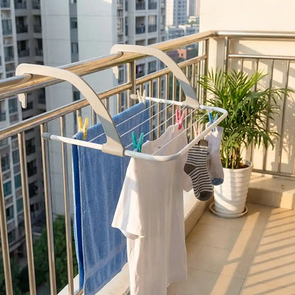 Folding clothes drying rack on balcony, holding shirts and socks with clothespins