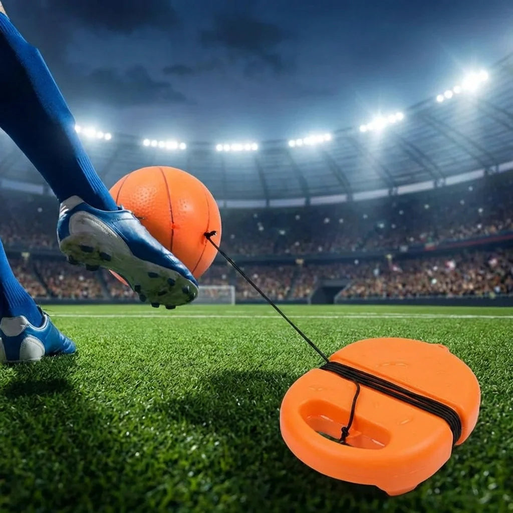 Football rebound ball set with string, orange ball near orange launcher base by soccer shoe