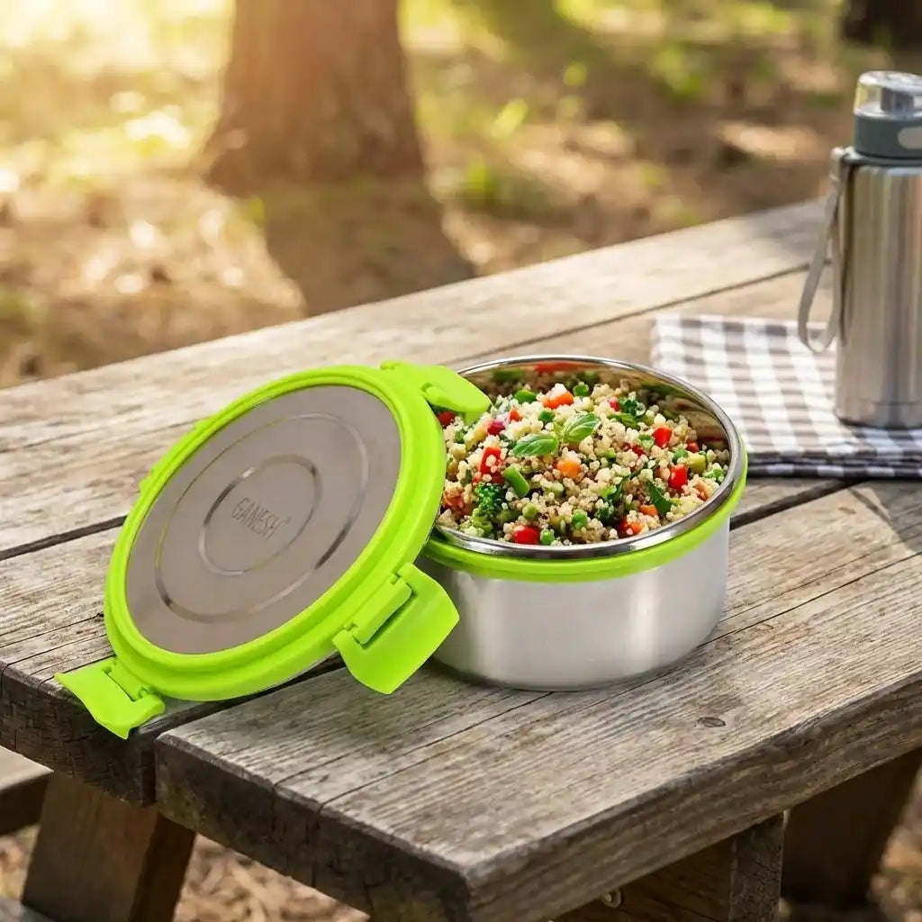 Open round stainless-steel lunch box with green hinged lid, filled with rice salad.
