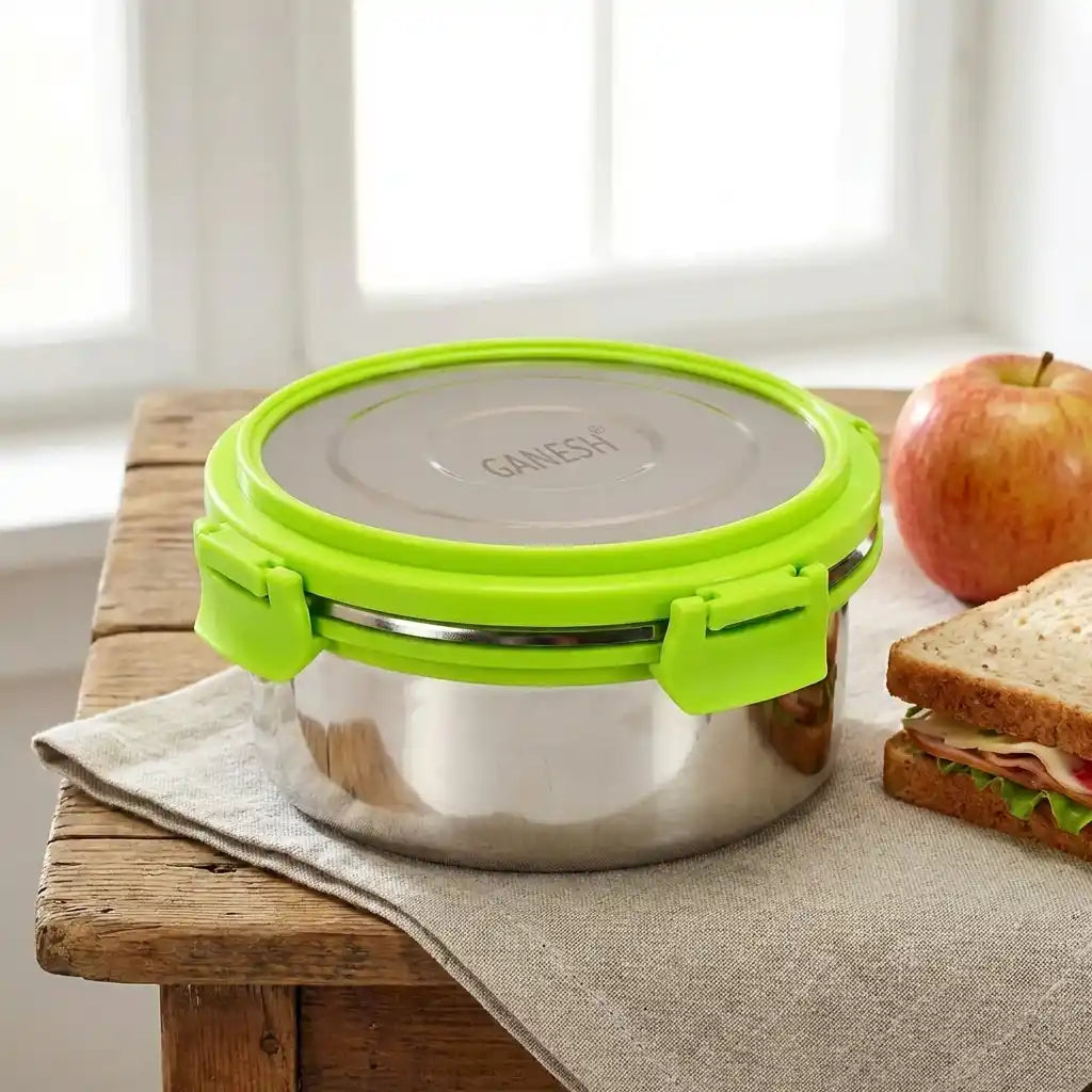 Round stainless lunch box with green snap handle and gray lid, closed.