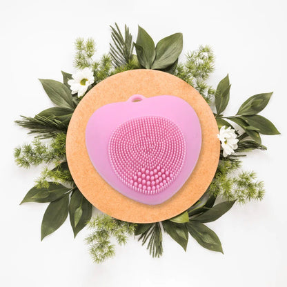 Face cleansing brush with pink silicone bristles in heart shape on circular base
