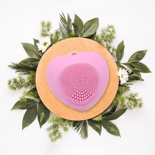 Face cleansing brush with pink silicone bristles in heart shape on circular base