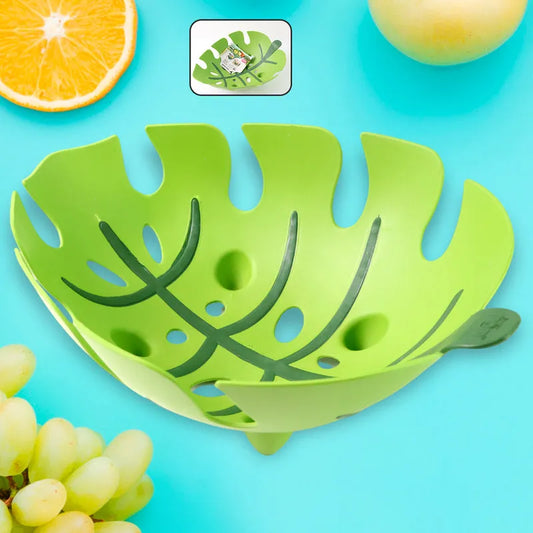 Green leaf-shaped fruit basket with cut-out leaf pattern and holes.