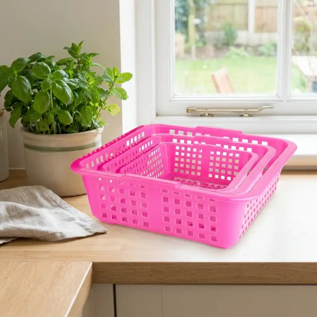 Plastic fruit basket with perforated sides, rectangular pink basket on a countertop