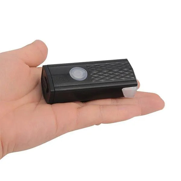Rechargeable bicycle light in hand, black body with small top indicator lens.
