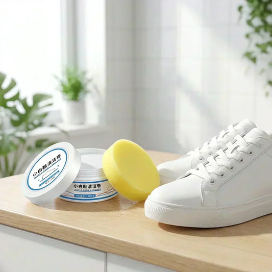 Shoe stain cleaning cream with round jar and yellow cleaning sponge beside white sneaker