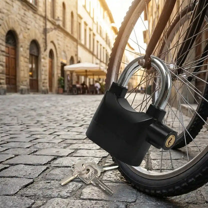 Siren Alarm padlock on motorcycle front wheel with two keys on pavement