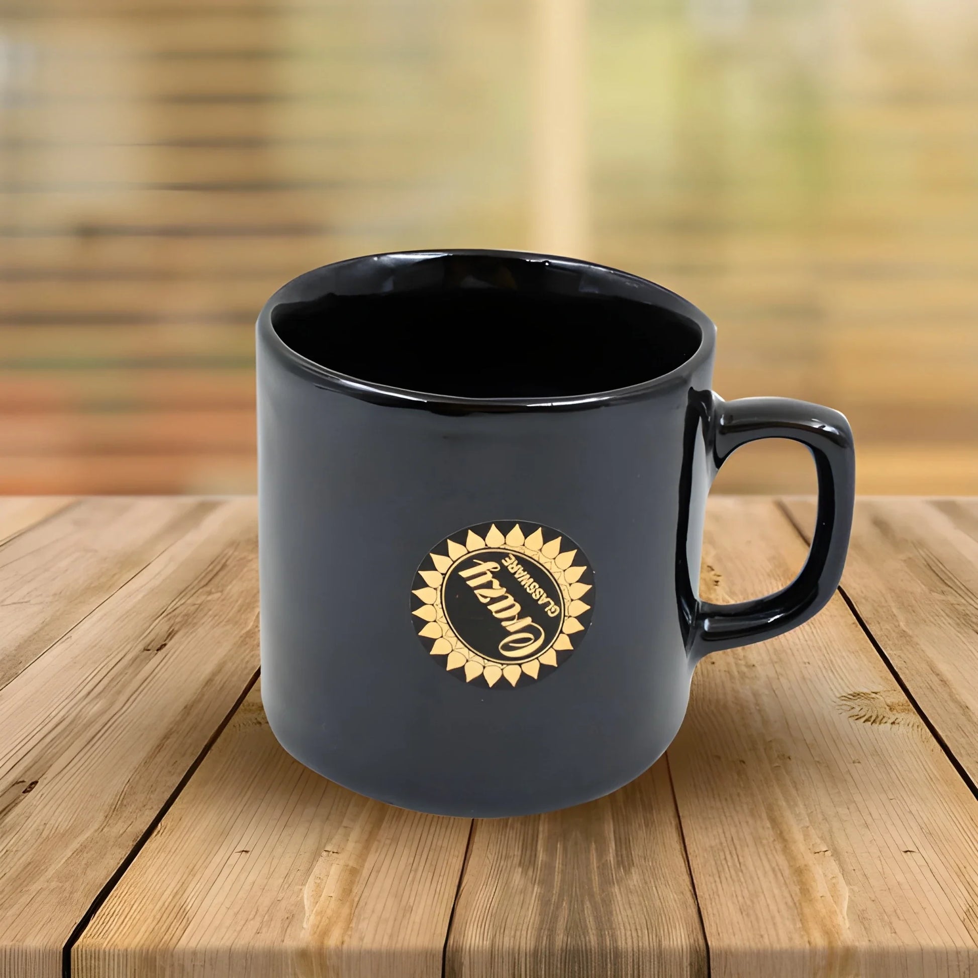Ceramic tea mug with handle, dark blue body and gold emblem on front