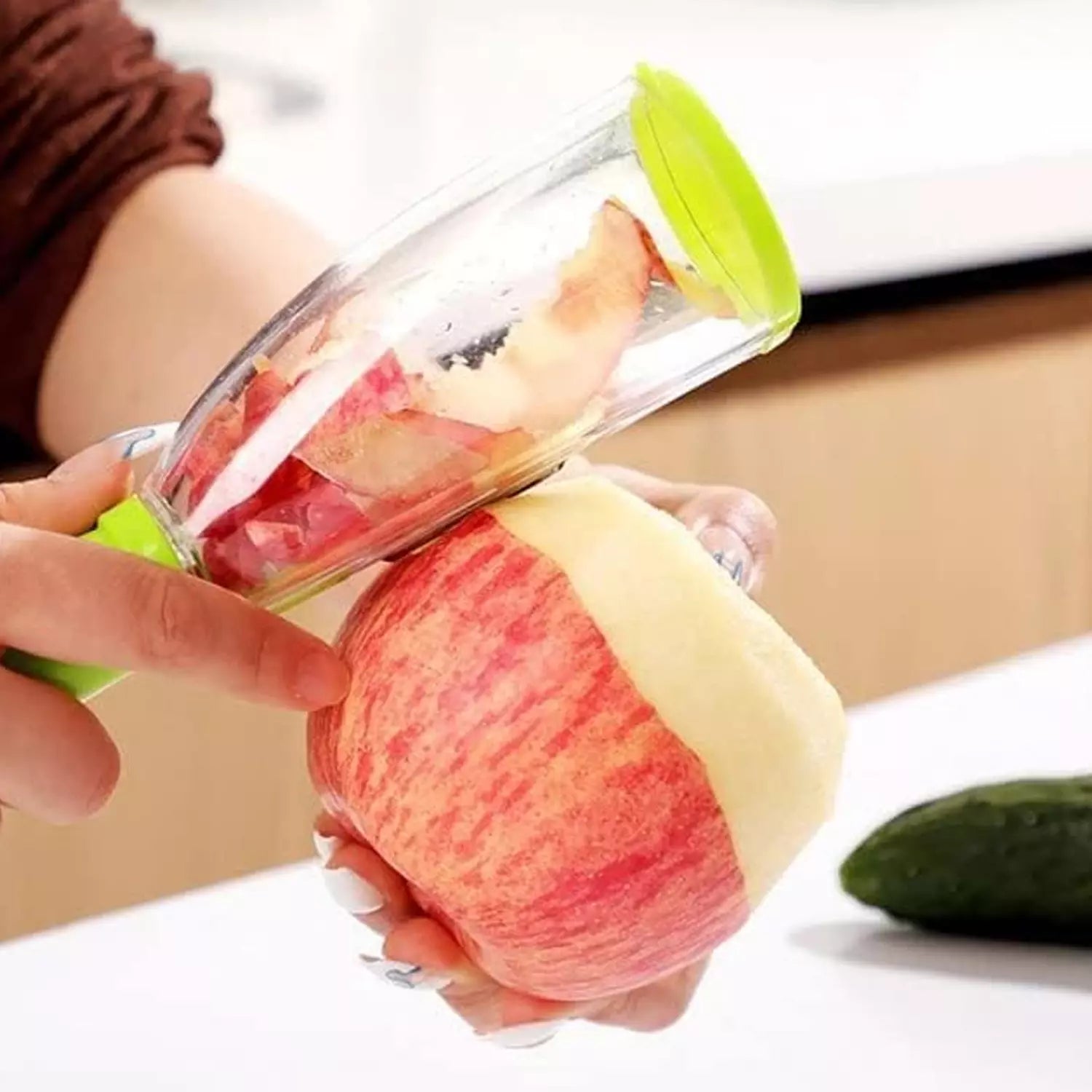 Smart peeler with catch container peeling a melon wedge, clear bin and green lid