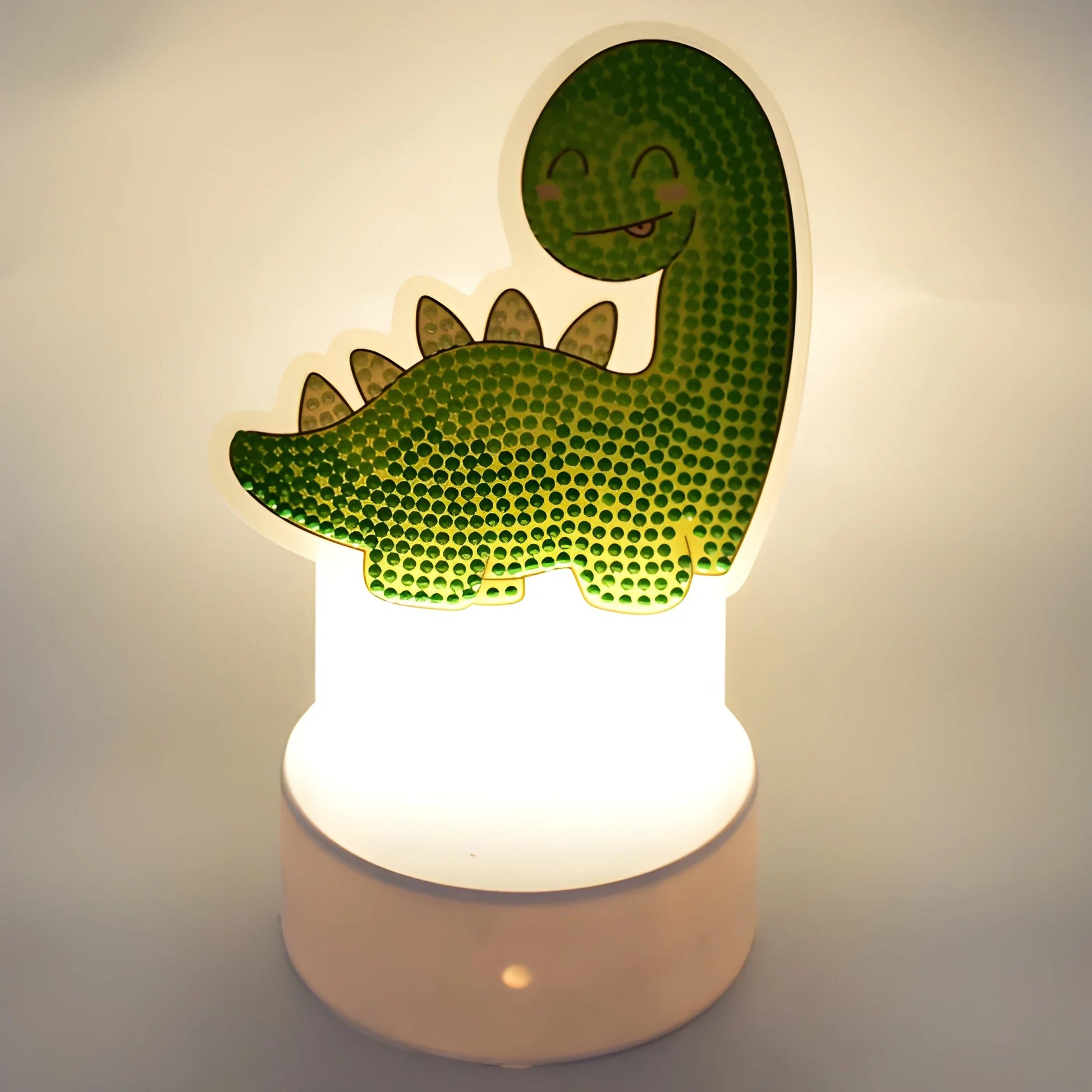 Kids night light with green dino shape on glowing base