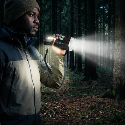Black LED torch light held in hand, front lens glowing with white beam