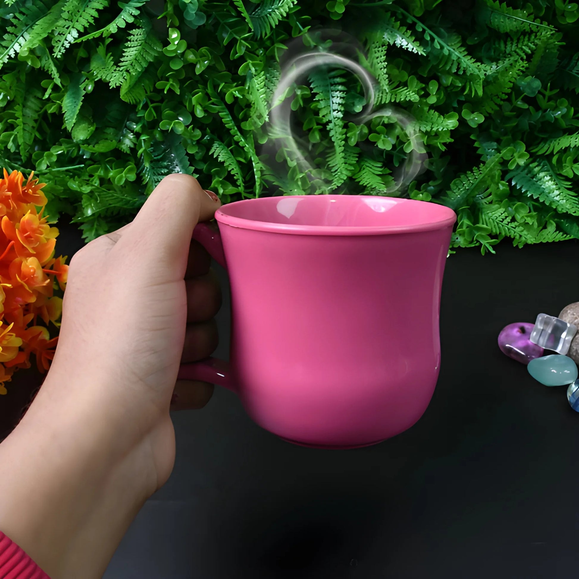Pink plastic coffee mug with handle, held by hand