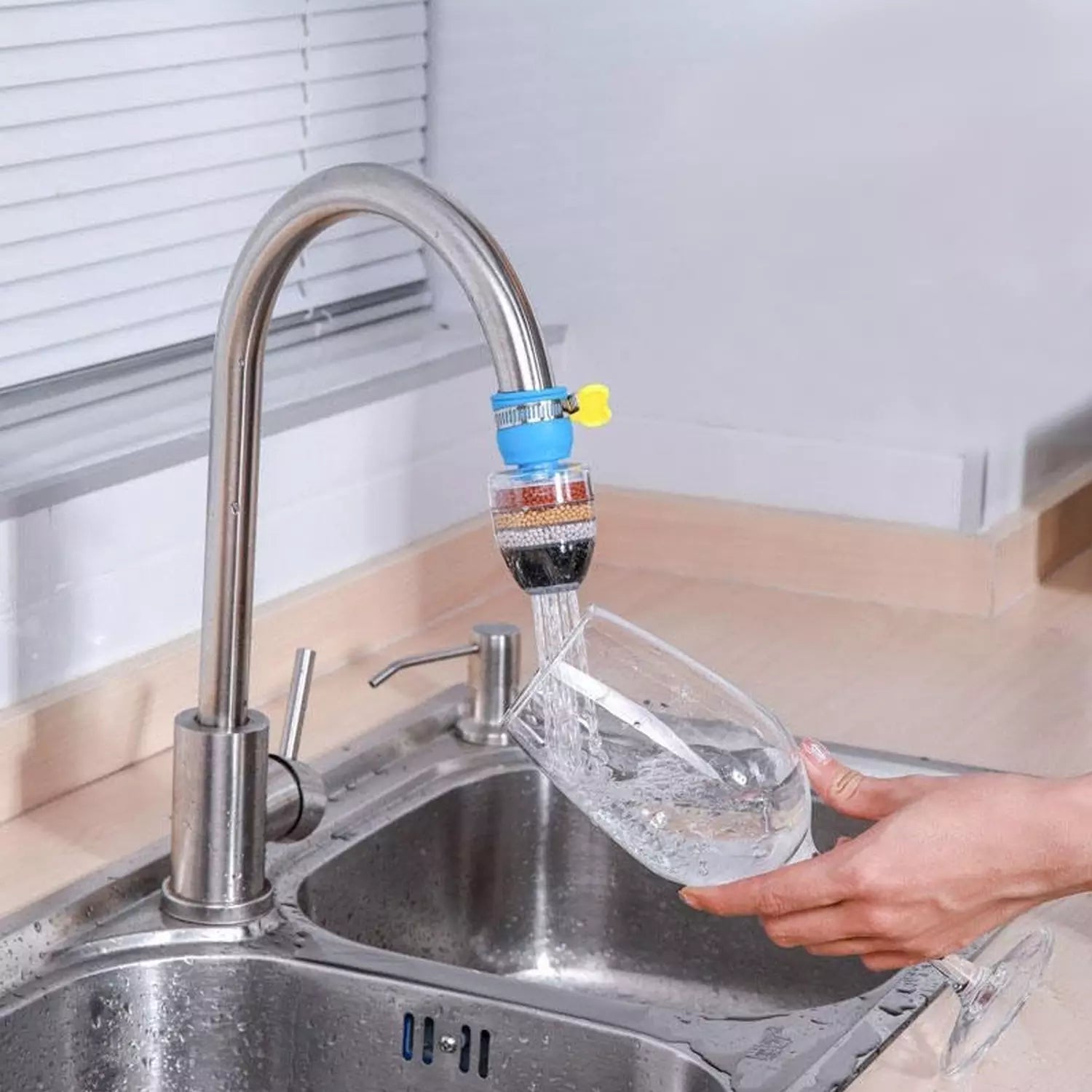 Universal faucet water filter with blue connector attached to kitchen faucet spout