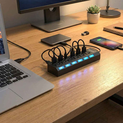 Black USB multi hub with multiple sockets and blue LED indicators on desk