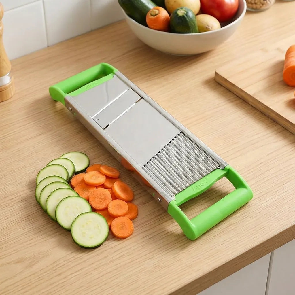2-in-1 vegetable slicer with green handles, metal blade, sliced cucumbers on counter