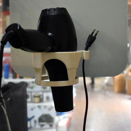 Wall-mount hair dryer holder holding a black hair dryer and power cord