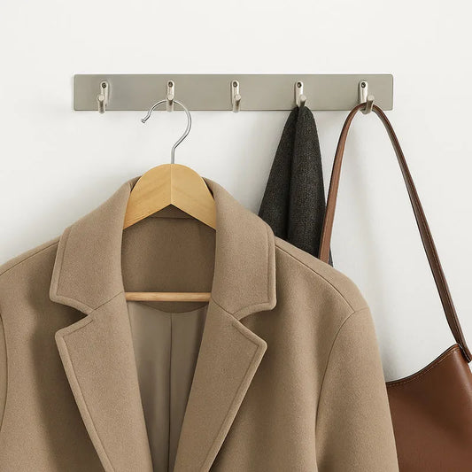 Wall mounted coat rack with five metal hooks, holding coats and handbags
